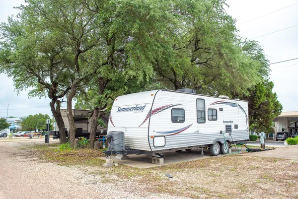 Travel trailer on a concrete pad under shade trees